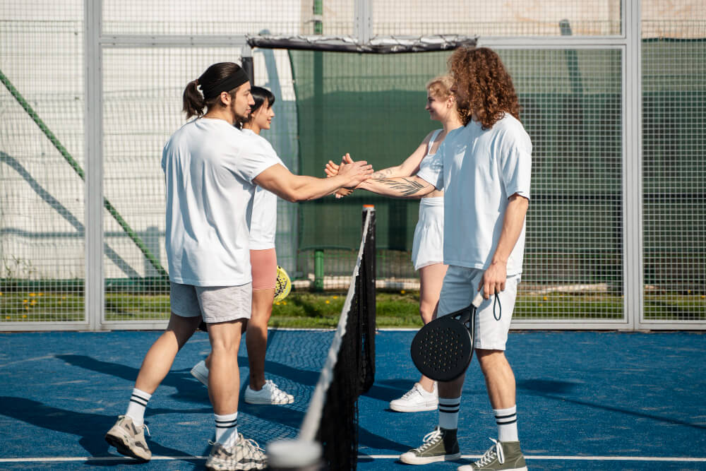 Joueurs de padel en plein match sur un court professionnel avec des spectateurs.