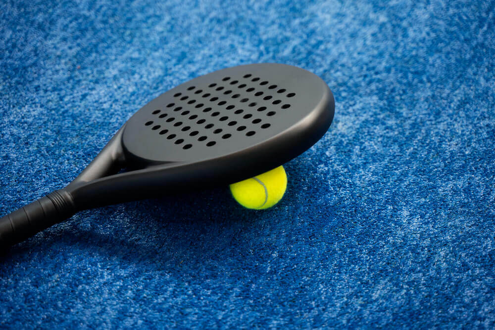 Gros plan sur la main d'un joueur tenant une raquette de padel, prêt à frapper.